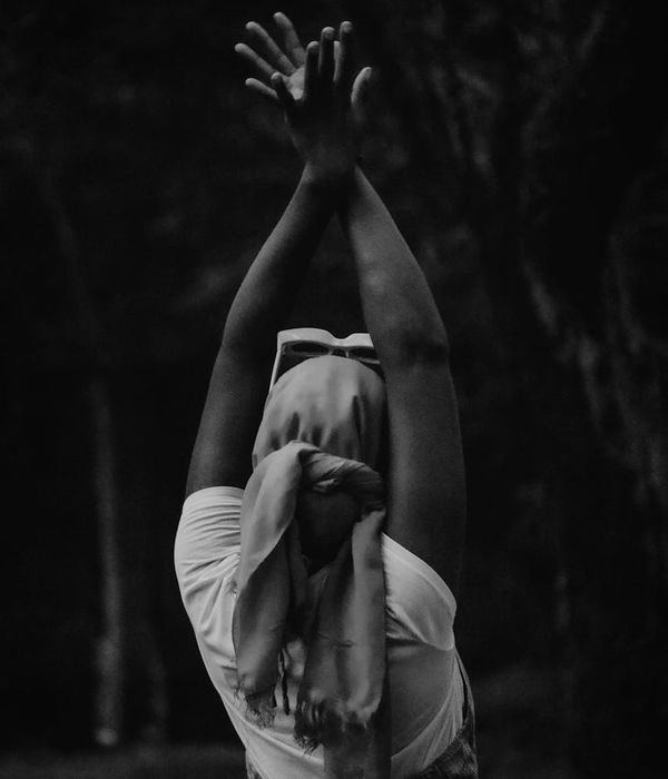 Woman in a calm yoga pose against a dark background.